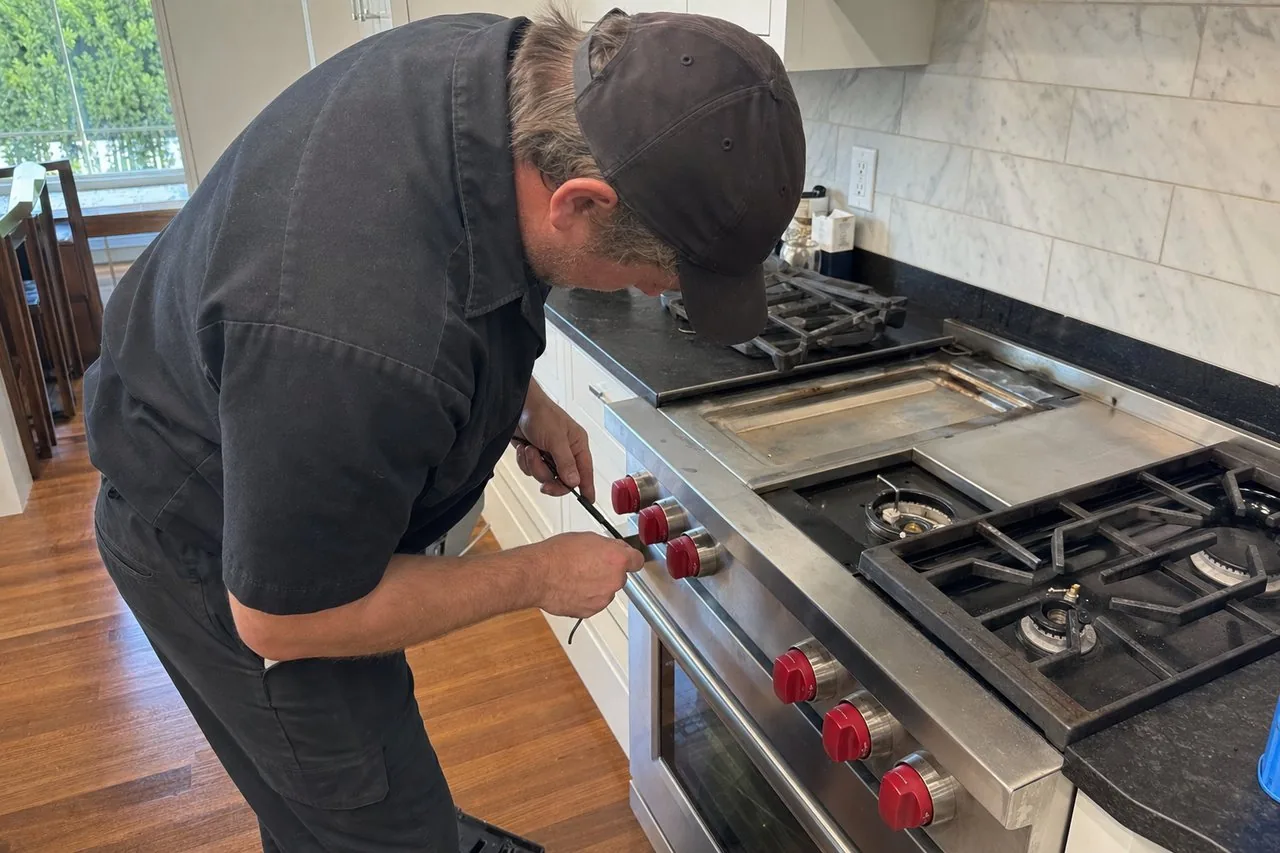 Technician servicing a stainless Wolf range in a Westchester home