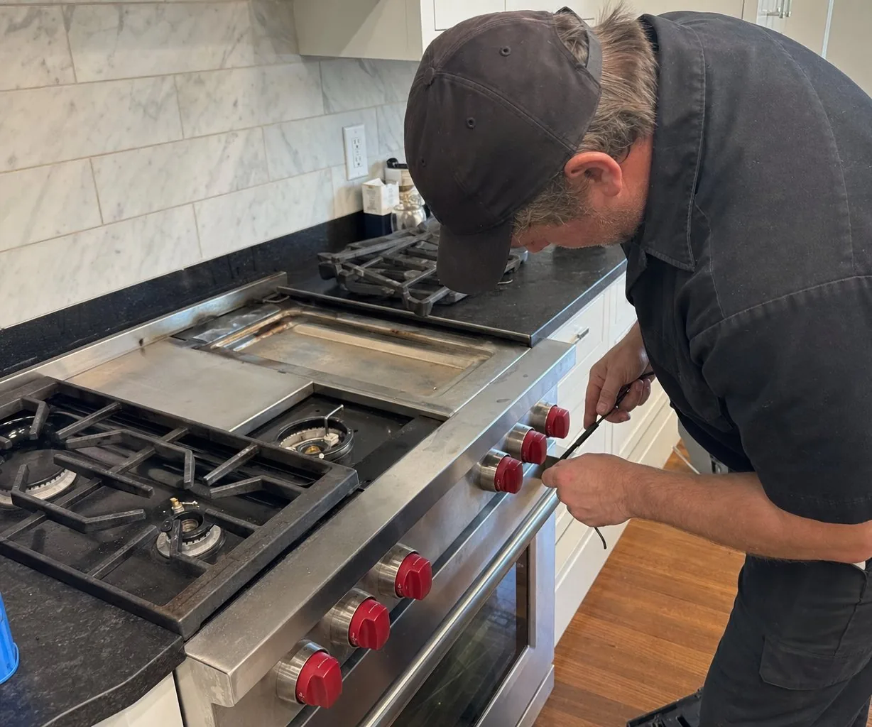 Technician servicing a stainless Wolf range in a Westchester home